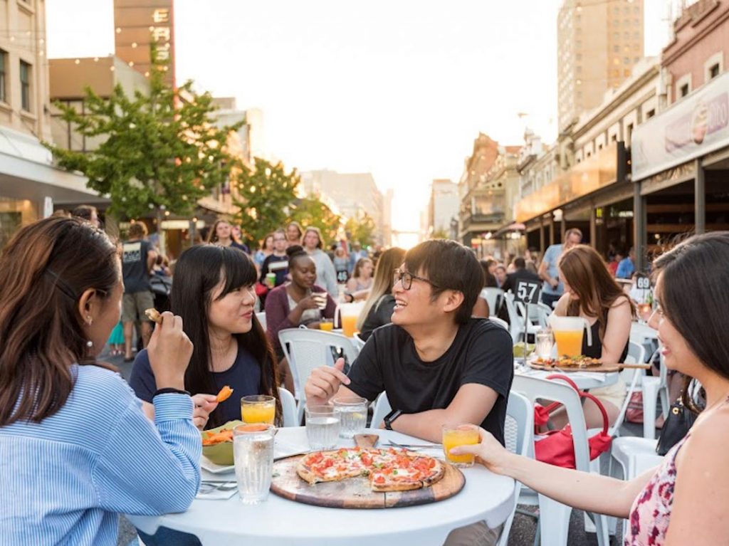 Jóvenes comen pizza en Adelaide