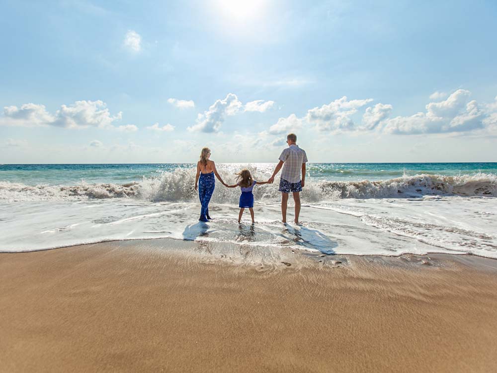 Joven pareja en una playa disfrutando a su hija estudiar en Australia con familia