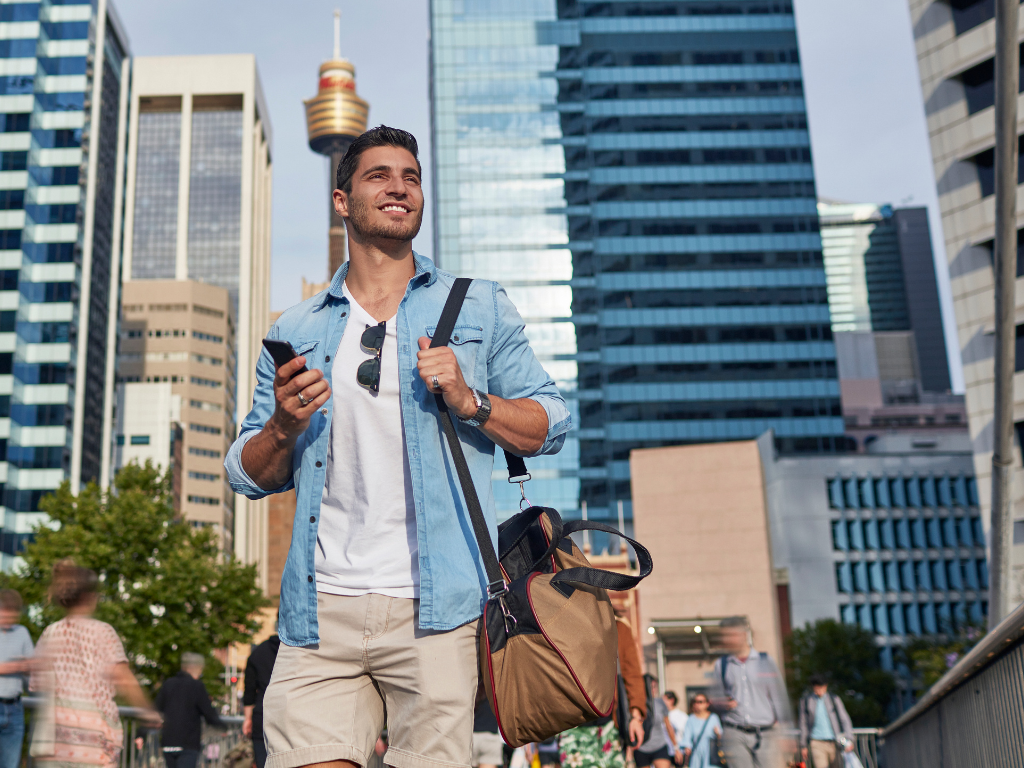 Joven hombre caminando por la ciudad de Sydney con una bolsa marrón
