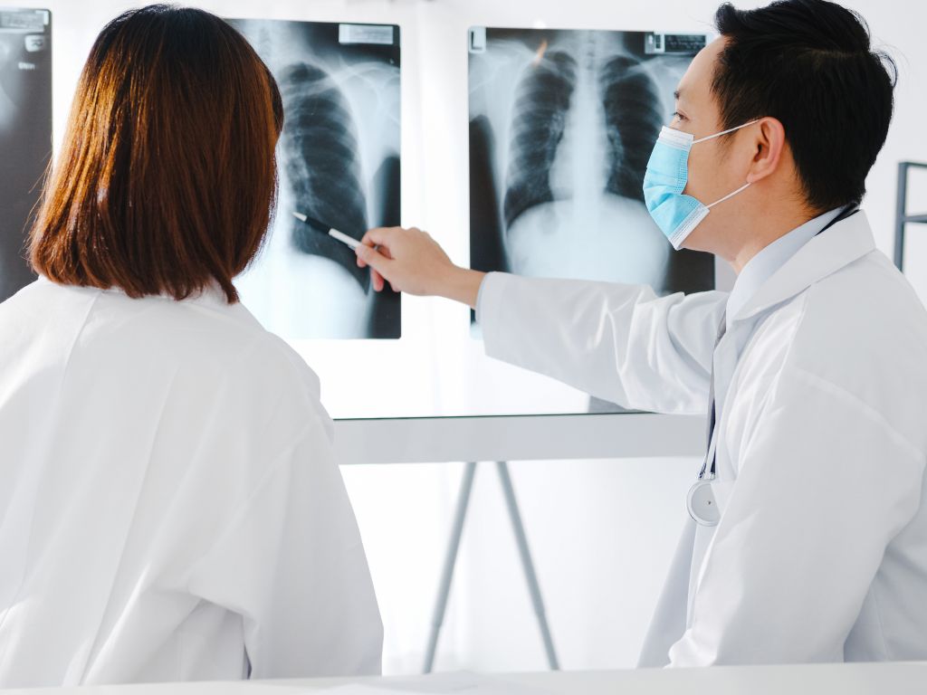 dos médicos un hombre y una mujer vestidos de blanco viendo dos radiografías