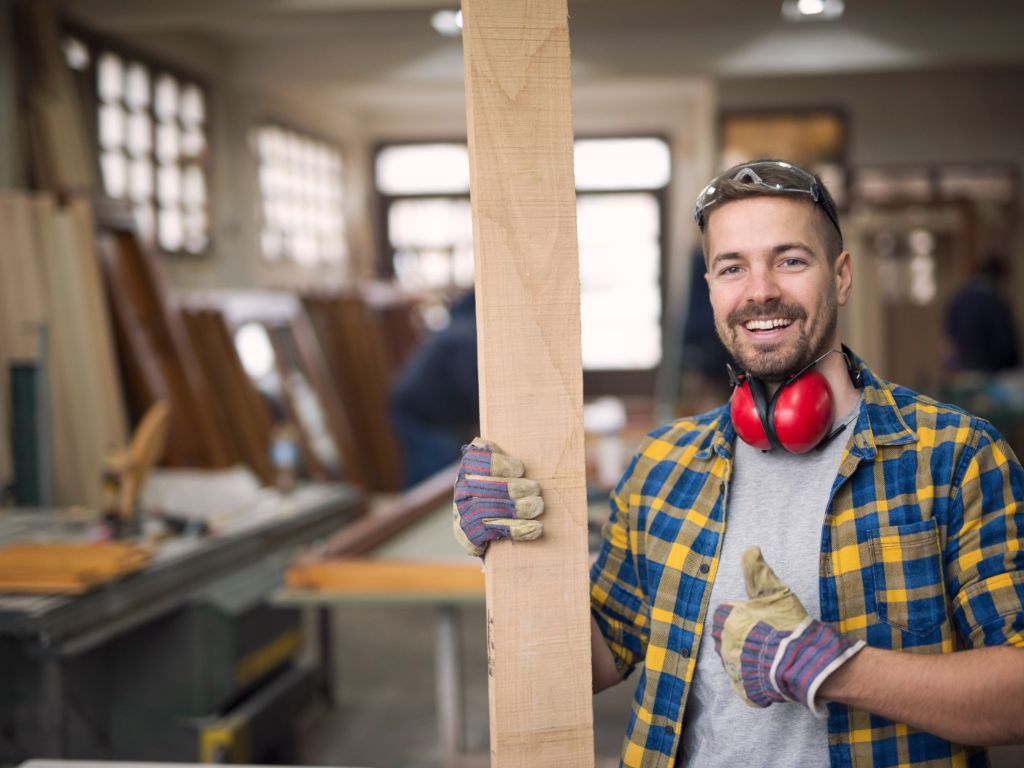 Hombre carpintero con una tabla en la mano en una carpintería cursos tafe en Australia