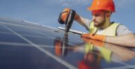 Joven ingeniero reparando un panel solar con casco naranja Australia visa 476